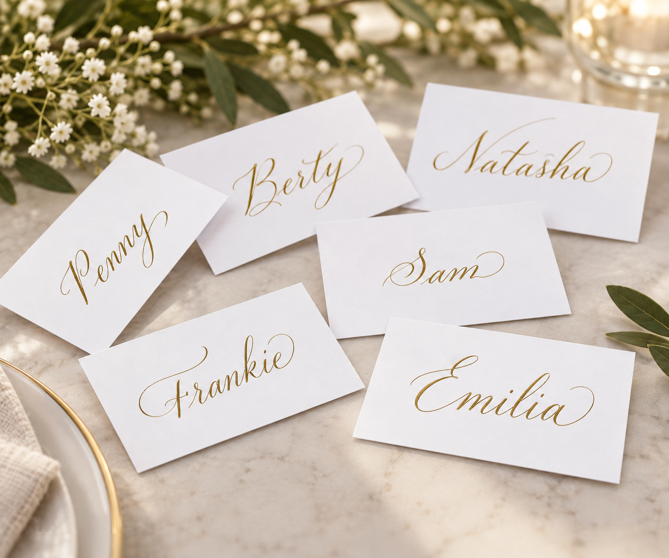 Wedding place cards handwritten in gold calligraphy on marble