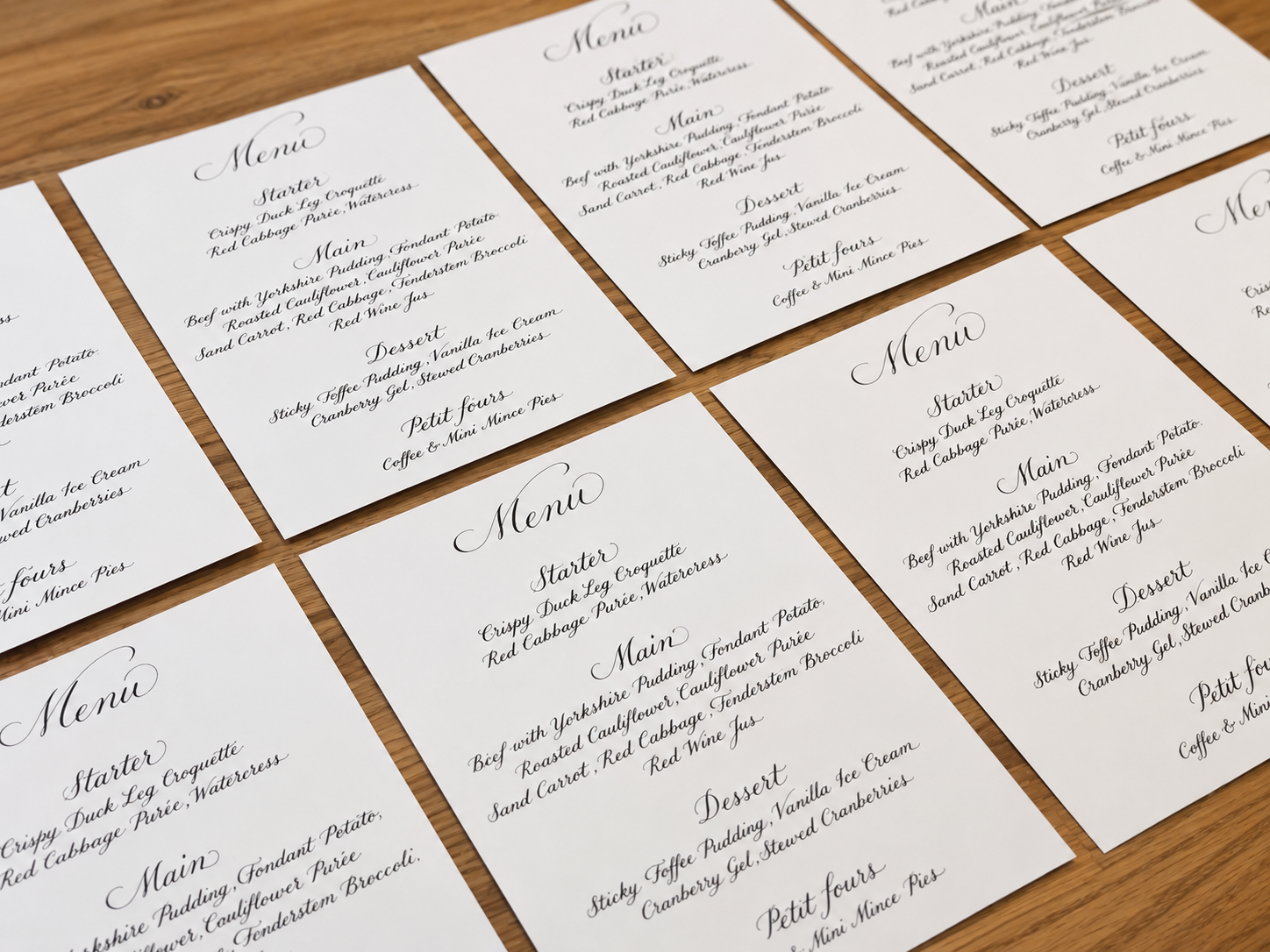 Handwritten calligraphy menus laid out on a wooden table